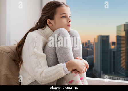 Sad girl sitting on sill à domicile sur la ville Banque D'Images