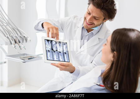 Handsome doctor showing patient x-ray résultat sur tablette numérique Banque D'Images