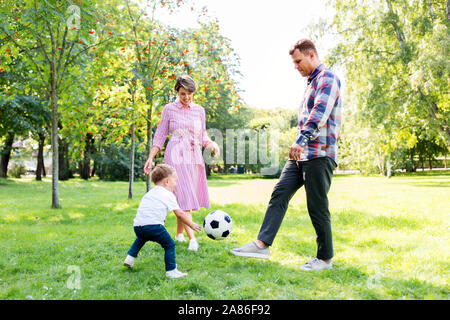 Famille heureuse à jouer au soccer au parc d'été Banque D'Images