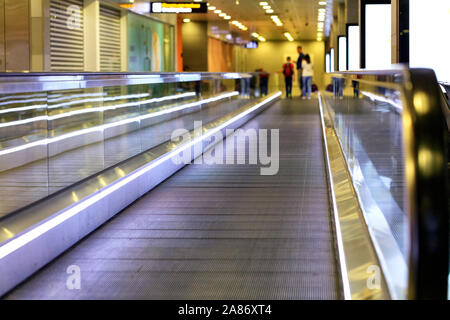 Le violet vif voie de transport à l'aéroport a une famille de voyageurs et de leurs bagages, brouillé le long du corridor. Banque D'Images