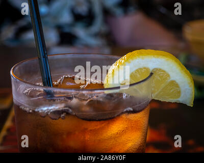 Cloaeup du bord supérieur du verre rempli de thé glacé avec une tranche de citron et de paille Banque D'Images