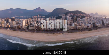 Tôt le matin dans la plage vide quartier d'Ipanema à Rio de Janeiro avec le Corcovado et pain de sucre dans le dos à une vague colorful sunrise Banque D'Images