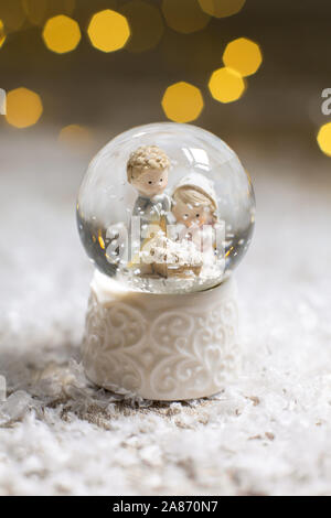 Sur le thème de Noël Décoration figurines. Une bille de verre avec des flocons de neige dans laquelle deux hommes se penchent sur le berceau, un symbole de la Nativité du Christ. Ch Banque D'Images