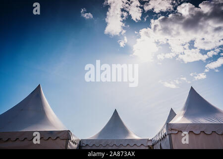 Sommets de trois tentes blanches pyramidale et fond de ciel bleu avec l'espace pour les annonceurs du texte. Banque D'Images