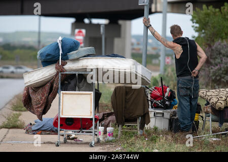 Ray Harvey piles ses affaires près d'un camp de sans-abri temporaire en vertu d'un viaduc en tant que travailleurs de l'état nettoyer le campement. Texas Gov. Greg Abbott a ordonné le retrait des camps de sans-abri sur les voies de passage publiques dans 17 sites autour de la ville. Banque D'Images