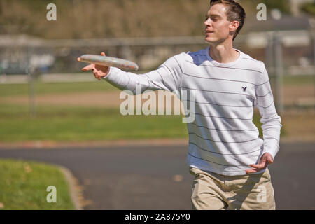 Jeune homme attraper un frisbee tandis que l'extérieur au soleil Banque D'Images