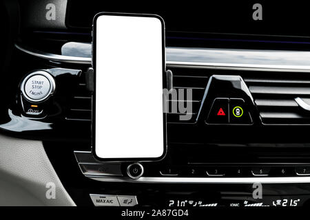 L'utilisation de la voiture dans un smartphone pour naviguer ou GPS. La conduite d'une voiture avec le smartphone dans le support. Téléphone mobile avec écran blanc isolé. Écran vide vide. Banque D'Images