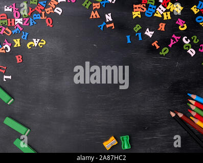 Les petites lettres en bois multicolores de l'alphabet anglais sur un tableau noir, l'espace de copie, le retour à l'école Banque D'Images