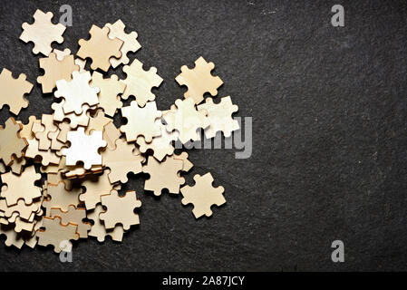 Chaos et confusion : détail de pièces de puzzle en bois mélangées sur fond noir. Concept de désorganisation et de problèmes. Banque D'Images