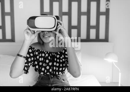 Young Asian teenage girl using casque de réalité virtuelle à la maison Banque D'Images