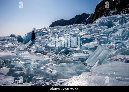 Une jeune fille se tient entre un grand tas de morceaux de glace brisée après une tempête sur le Lac Baïkal. Journée ensoleillée, la glace brille au soleil. Ciel bleu sans nuages. Banque D'Images