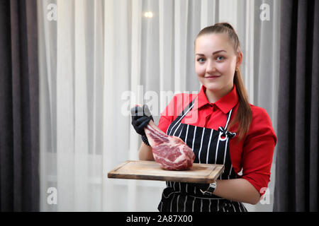 Les serveuses de fille avec des steaks. Steak grillé moyennes coupées en morceaux sur une planche de bois. Banque D'Images