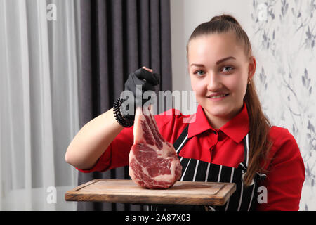 Les serveuses de fille avec des steaks. Steak grillé moyennes coupées en morceaux sur une planche de bois. Banque D'Images