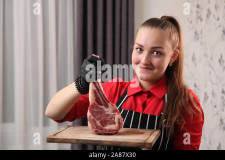 Les serveuses de fille avec des steaks. Steak grillé moyennes coupées en morceaux sur une planche de bois. Banque D'Images