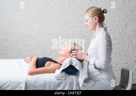 Les professionnels donnant masseur massage relaxant aux jeunes femmes client. Mains de masseuse sur le front du jeune femme lors de la procédure de Banque D'Images