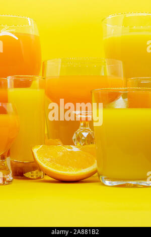 Composition abstraite de jus d'orange et de jaune en forme de boissons diverses lunettes avec tranche d'orange et de fruits sur fond jaune avec l'exemplaire Banque D'Images