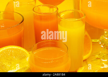 Composition abstraite de jus d'orange et de jaune en forme de boissons diverses lunettes avec des tranches de fruits orange et placés sur fond jaune avec l'exemplaire Banque D'Images