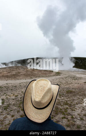 - YELLOWSTONE Un touriste avec un Stetson watches le geyser à l'Old Faithfull Banque D'Images