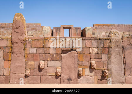 Pierres de mortaise-chefs sur la semi-Temple souterrain avec le Temple Kalasasaya en arrière-plan sur le complexe archéologique de Tiwanaku, Bolivie Banque D'Images