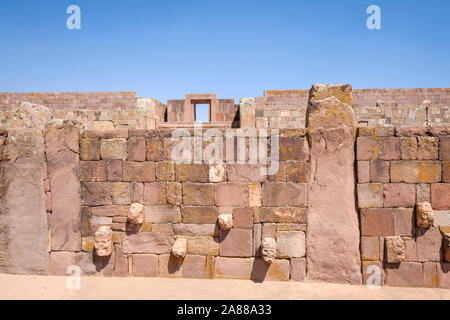 Pierres de mortaise-chefs sur la semi-Temple souterrain avec le Temple Kalasasaya en arrière-plan sur le complexe archéologique de Tiwanaku, Bolivie Banque D'Images