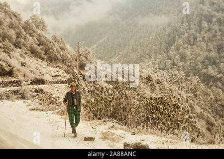 Une vieille mature (un homme d'ethnie Népalaise) randonneur solitaire sur un sentier de randonnée à pied tout seul dans un bel environnement d'hiver du nord-est de l'Himalayan Mo Banque D'Images