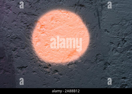 Cercle orange sur le mur noir arrière-plan. La texture du mur peint. Surface en pierre avec des irrégularités et des trous. Banque D'Images
