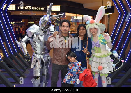 Une famille asiatique pose avec costume homme et robot girl costume de lapin avec des lumières à l'arrière-plan en Cameron Highlands, Malaisie, Asie. Banque D'Images