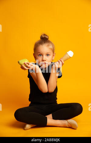 Perplexe Petite danseuse de choisir entre la poire et de la crème glacée Banque D'Images