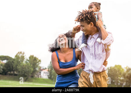 Happy African family enjoying ensemble dans un parc public - Mère, père et fille s'amusant pendant un week-end journée ensoleillée piscine