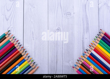 Crayons en bois, dans les coins inférieurs d'un fond de bois blanc et gris Banque D'Images