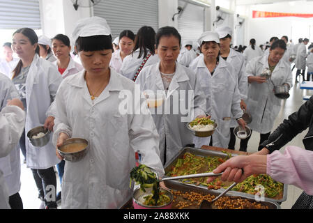 (191107) -- LINYI, 7 novembre 2019 (Xinhua) -- Pang Shuidi (1re L), Wu, l'épouse de Caizhong se prépare à être servi avec déjeuner dans une entreprise dans le comté de Linyi, Chine du Sud, région autonome Zhuang du Guangxi, le 6 novembre 2019. 205 de l'entreprise, les travailleurs sont déplacés de 71 ménages. Wu est un Caizhong 36 ans ethnique Mulao. Sa famille, avec d'autres personnes ethniques Mulao, utilisé pour vivre à Xiayantun de Mianhua Village, un village en proie à un développement inadéquat en raison de la désertification et les pauvres rocheuses karstiques des conditions de circulation. En juin 2018, la famille de Wu et d'autres villageois ont été réinstallés dans un Banque D'Images