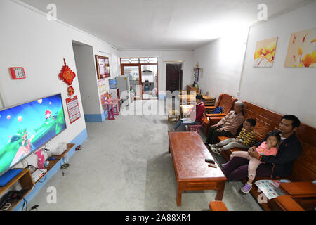 (191107) -- LINYI, 7 novembre 2019 (Xinhua) -- Caizhong Wu et sa famille regardent la télévision dans leur nouvelle maison dans le comté de Linyi, Chine du Sud, région autonome Zhuang du Guangxi, le 6 novembre 2019. Wu est un Caizhong 36 ans ethnique Mulao. Sa famille, avec d'autres personnes ethniques Mulao, utilisé pour vivre à Xiayantun de Mianhua Village, un village en proie à un développement inadéquat en raison de la désertification et les pauvres rocheuses karstiques des conditions de circulation. En juin 2018, la famille de Wu et d'autres villageois ont été transférés dans une nouvelle zone résidentielle pour les personnes ethniques Mulao à Linyi. Cette zone résidentielle, avec mu Banque D'Images