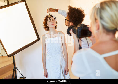 Maquilleuse ou maquilleur appliquant le maquillage d'une mariée dans un studio photo Banque D'Images