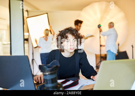 Photographe sur ordinateur portable de la photo studio pendant le traitement de l'image ou la sauvegarde des données Banque D'Images