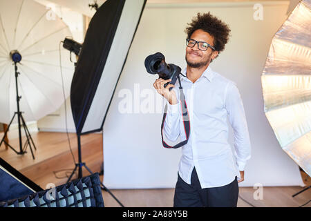 Jeune photographe créatif dans le studio photo avec l'appareil photo reflex Banque D'Images