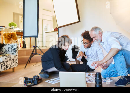 Photo photographe avec assistant et directeur artistique à la sélection de photos dans le studio photo Banque D'Images