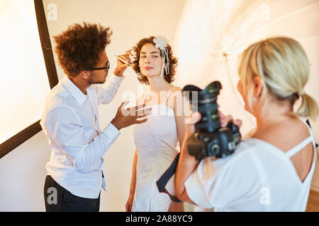 Make-up artist styling la mariée pour la pousse de photo le jour du mariage Banque D'Images