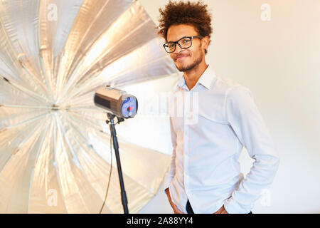 Jeune homme comme un modèle ou un photographe en face de lampe torche avec studio Banque D'Images