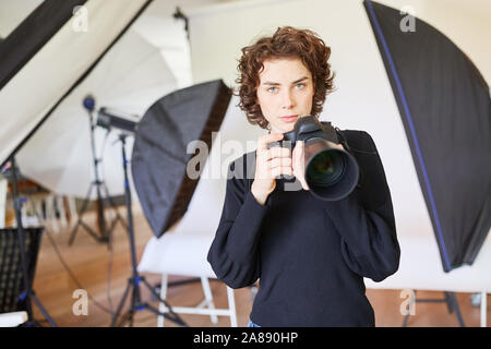 Confiant le jeune photographe avec appareil photo numérique dans la photo studio Banque D'Images