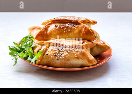 Samsa. Galettes de viande oriental traditionnel avec les feuilles de persil sur une assiette Banque D'Images