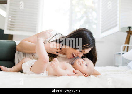 Mère souriante couchée avec son fils au lit Banque D'Images
