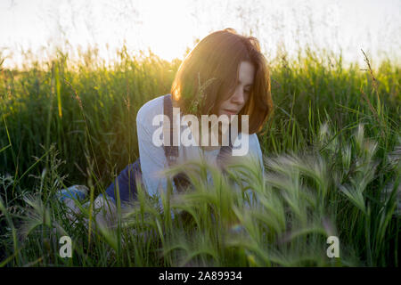 Jeune femme assise dans un champ de blé Banque D'Images
