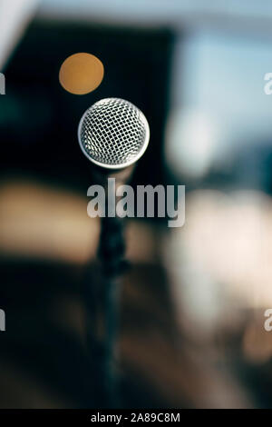 MIC SUR UN STADE PRÊT POUR LE CHANTEUR OU LE PRÉSIDENT AVEC BCKGROUND BROUILLÉE ET LA COULEUR DE L'ARRIÈRE. Banque D'Images