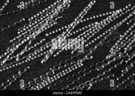 Extreme close up, de haut en bas vue de polypropylène fibres macro sinusoïdal pour le renforcement du béton sur fond noir en noir. L'industrie de la construction Banque D'Images