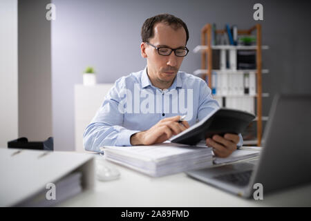 Au cours de l'épaule de l'homme d'affaires Le calcul de l'aide de factures Calculator Banque D'Images