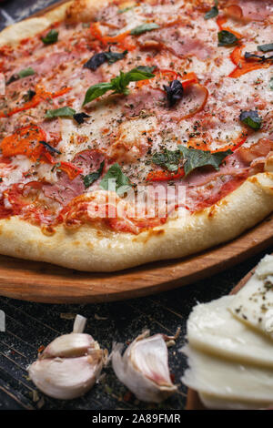Pizza italienne en gros plan. Pizza fraîche au jambon et au basilic. Banque D'Images
