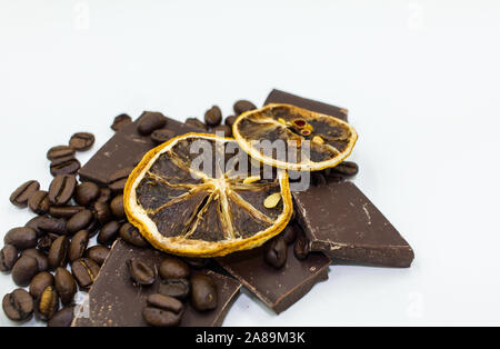 Tranches d'orange séchée sur le dessus des morceaux de chocolat et les grains de café - Fond blanc Banque D'Images