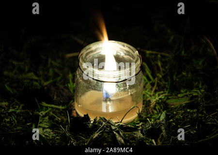 Bougie dans un bocal en verre dans l'herbe. La vie nocturne de plantes dans le jardin Banque D'Images