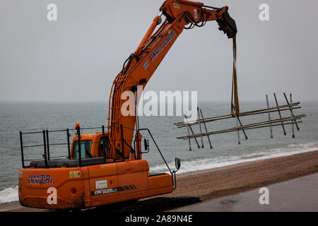 Des ouvriers avec des machines lourdes réparer le mur de protection contre les inondations à Torcross, Devon. Banque D'Images