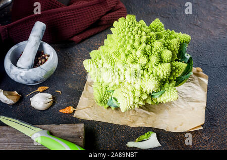 Frais vert, Chou romanesco biologiques crus prête pour la cuisson sur une planche à découper sur fond de bois foncé Banque D'Images